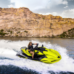 Une femme sur un Jet ski Kawasaki Ultra 310X 2026 jaune neon et noir ebony sur un lac avec un arrière plan rocheux